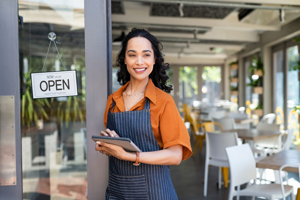 Small business entrepreneur at cafe entrance using digital table